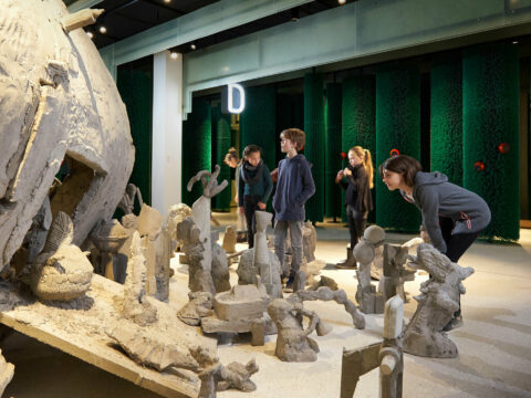 K | KLEINWESEN | Foto: Nikolaus Frank Kinder in der Ausstellung vor dem Kunstwerk "Märchenbombe" aus Beton und Mörtel.