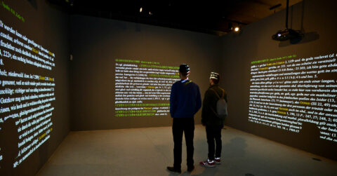 S | SPRACHSCHATZ | Foto: Andreas Berthel Zwei Personen stehen in einem Raum mit an die Wand projizierten Wörterbuchartikeln.