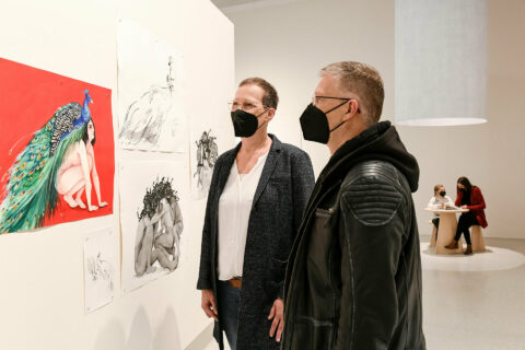 Sonderausstellung Necla Ruezgar | Zwei Besucher*innen vor einem Aquarell | Foto: Nils Klinger Zwei Menschen betrachten ein Aquarell von Necla Rüzgar.