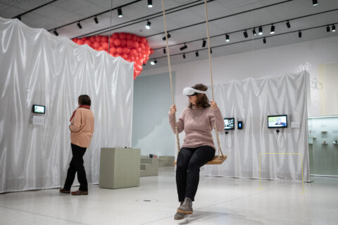 Sonderausstellung unMÖGLICH | Die Magie der Wünsche | Foto: Sascha Mannel Frau sitzt auf Schaukel mit VR-Brille
