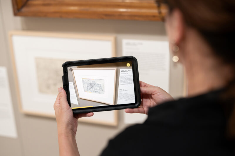 Sonderausstellung AKTE RUMPELSTILZCHEN | App | Foto: Nicolas Wefers Frau blickt in das Tablett mit der App