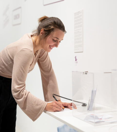 Sonderausstellung AKTE RUMPELSTILZCHEN | Foto: Nicolas Wefers Frau schreibt ihr Geheimnis auf einen Zettel