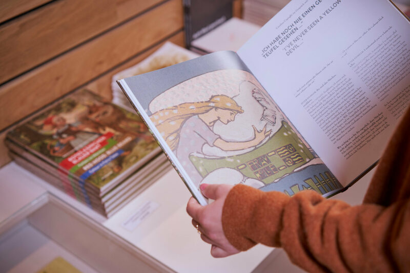 GRIMMWELT | Sonderausstellung | Publikation Rotes Käppchen, blauer Bart | Foto: Nikolaus Frank Aufgeschlagene Publikation Rotes Käppchen, blauer Bart. Innenseite mit Märchenmotiv.