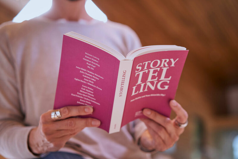 GRIMMWELT | Sonderausstellung | Publikation Storytelling | Foto : Nikolaus Frank Eine Frau hält die Publikation Storytelling in ihren Händen.