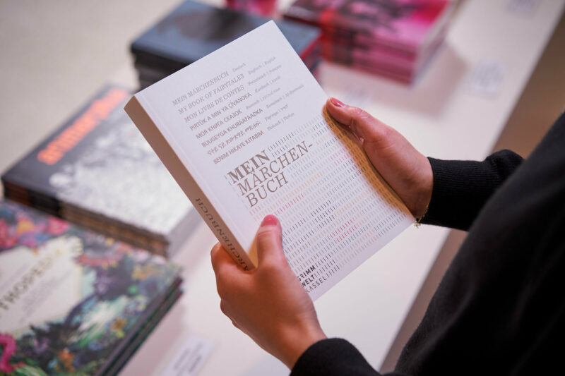 GRIMMWELT | Sonderausstellung | Publikation Mein Märchenbuch | Foto: Nikolaus Frank Jemand hält die Publikation Mein Märchenbuch in Händen.