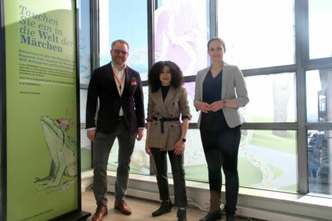 GRIMMWELT zu Gast in der GALERIA | Eröffnungsempfang zu Ausstellungsbeginn | Foto: Kurt U. Heldmann Drei Personen stehen vor den Illustrationen in der GALERIA Kassel.