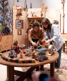 10 | Die Werkstatt der Lhotaks | IMAGINARIUM | (c) GRIMMWELT Kassel, Foto Nicolas Wefers Besucherinnen spielen mit Holzfiguren in der Werkstatt der Lhotáks.