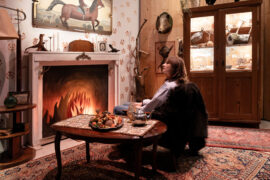 13 | Kabinett | IMAGINARIUM | (c) GRIMMWELT Kassel, Foto Nicolas Wefers Eine Frau sitzt in einem Raum udn schaut sich um