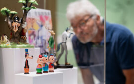 10 | Ausstellung ICH, DAS TIER | Wölfe | © GRIMMWELT Kassel, Foto Nicolas Wefers Mann steht vor Vitrine mit Merchandiseartikeln