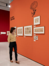 13 | Ausstellung ICH, DAS TIER | Gus Dirks | © GRIMMWELT Kassel, Foto Nicolas Wefers Eine Frau geht an der Wand zum Gus Dirks vorbei