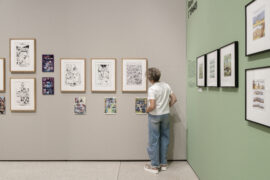 17 | Ausstellung ICH, DAS TIER | Fables | © GRIMMWELT Kassel, Foto Nicolas Wefers Frau schaut sich Fables-Illustrationen von Mark Buckingham an