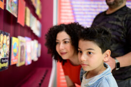 13 Märchenbücher | © GRIMMWELT Kassel | Foto: Sascha Mannel Eine Frau und ein Kind betrachten Märchenbücher.