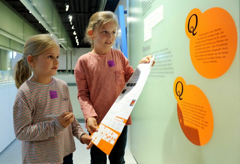 Q | QUITTE | Mädchen mit dem Flyer "Weltreise" | Foto: Harry Soremski Zwei Mädchen entdecken mit der WELTREISE-Schatzkarte die GRIMMWELT.