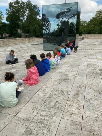 GRIMMWELT | Grimms Märchenjurte | Um die Häuser ziehen Kinder sitzen auf dem Dach der GRIMMWELT.