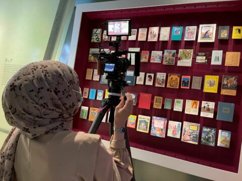 V | VOLKSMÄRCHEN | Smart Museums TV in der GRIMMWELT | Foto: Gabriel Chiarello Ein Mädchen filmt ausgestellte Märchenbücher.